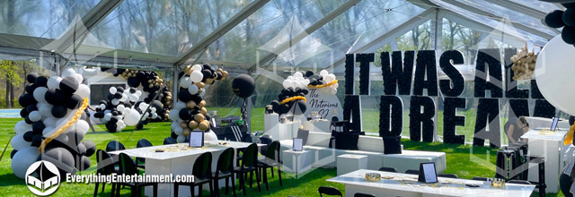 Clear top tent in a backyard with black, white, and white decor