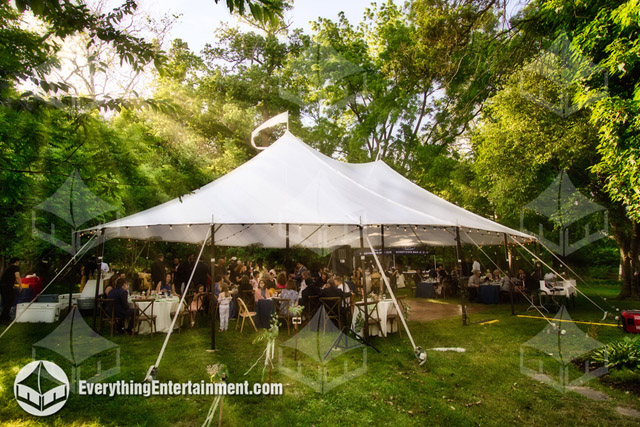A large sailcloth tent for a backyard wedding with guests seated underneath.