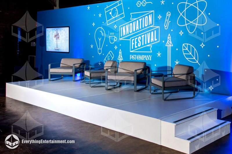 White stage with blue backdrop and white lounge chairs for a corporate presentation in Manhattan