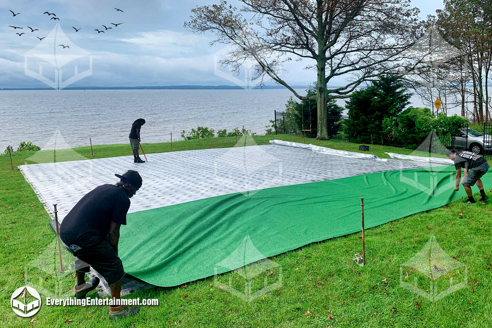 Green turf being installed over a tent subfloor.